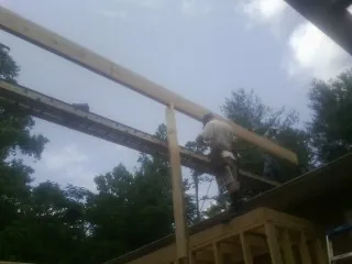 Carpenter setting a ridge beam over a new addition frame — Ice Dam Removal by Roofing Brothers in Alexandria